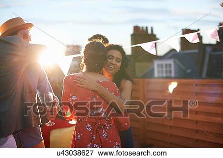 Stock Photo - Friends congratulating couple at early evening engagement party. Fotosearch