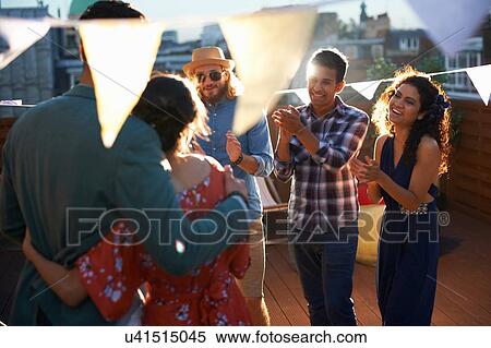 Stock Photography - Friends congratulating couple at early evening engagement party. Fotosearch