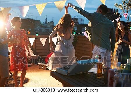 Stock Image - Friends dancing at early evening party. Fotosearch