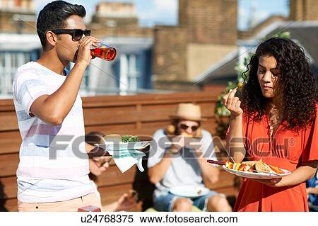 Friends eating party food and drinking at rooftop party View Large Photo Image Stock Photography - Friends eating party food and drinking at rooftop party. Fotosearch
