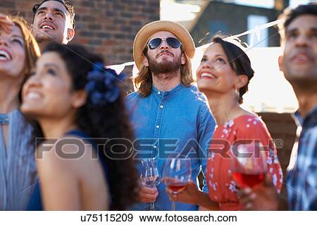 Stock Photo - Friends looking up overhead at early evening party. Fotosearch