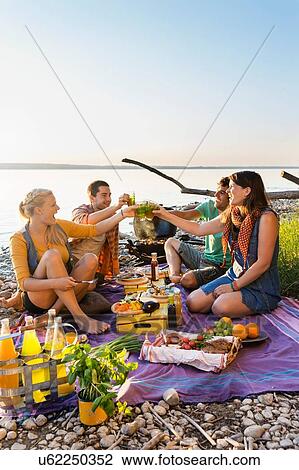 Friends sitting next to water haing a picnic making a toast, Schondorf, Ammersee, Bavaria, Germany View Large Photo Image Stock Image - Friends sitting next to water haing a picnic making a toast, Schondorf, Ammersee, Bavaria, Germany. Fotosearch