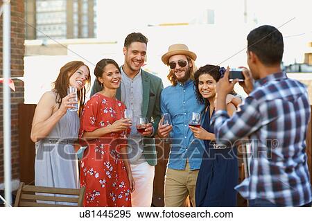 Stock Photography - Friends taking photograph at early evening party. Fotosearch