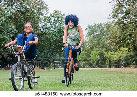 Front view of mother and son riding on bicycles smiling View Large Photo Image Stock Image - Front view of mother and son riding on bicycles smiling. Fotosearch