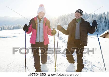 Front view of senior couple on snow covered landscape holding walking poles looking at camera, Sattelbergalm, Tyrol, Austria View Large Photo Image Stock Image - Front view of senior couple on snow covered landscape holding walking poles looking at camera, Sattelbergalm, Tyrol, Austria. Fotosearch