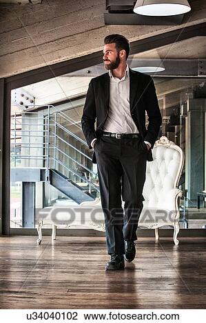 Full length front view of mid adult man wearing suit hands in pockets looking away View Large Photo Image Stock Image - Full length front view of mid adult man wearing suit hands in pockets looking away. Fotosearch