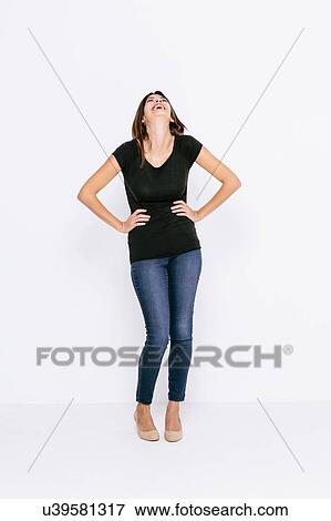Stock Photo - Full length front view of young woman, hands on hips, head back laughing. Fotosearch