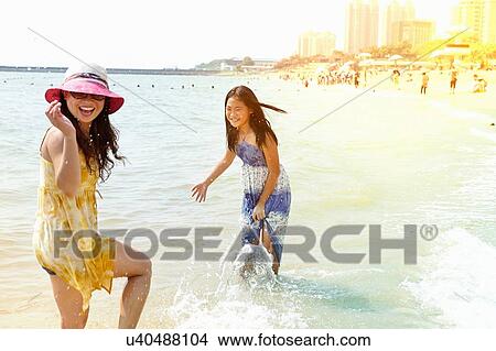 Picture - Girl and mother splashing in sea, Zhuhai, Guangdong, China. Fotosearch