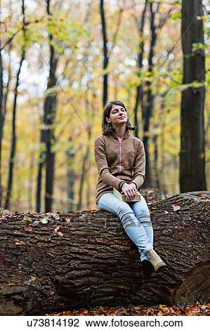 Girl daydreaming on tree trunk in autumn forest View Large Photo Image Stock Image - Girl daydreaming on tree trunk in autumn forest. Fotosearch