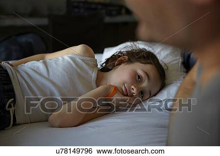 Girl lying on bed watching father View Large Photo Image Stock Photograph - Girl lying on bed watching father. Fotosearch