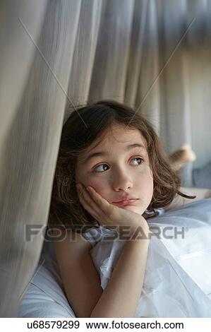 Stock Photo - Girl reclining on bed gazing sideways. Fotosearch
