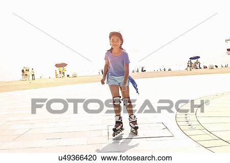 Stock Image - Girl rollerblading at beach, Zhuhai, Guangdong, China. Fotosearch