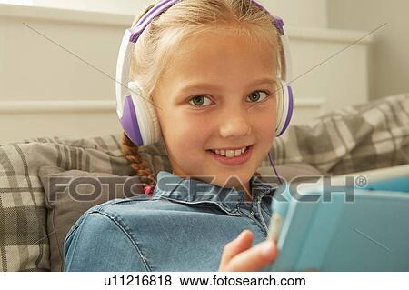 Girl wearing headphones holding digital tablet looking at camera smiling View Large Photo Image Stock Photo - Girl wearing headphones holding digital tablet looking at camera smiling. Fotosearch