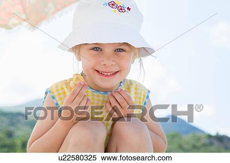 Stock Photography - Girl wearing sunhat eating doughnut. Fotosearch