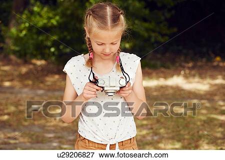 Girls holding film camera looking down View Large Photo Image Stock Photo - Girls holding film camera looking down. Fotosearch