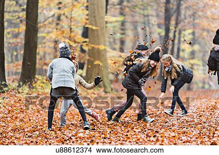 Girls playing with leaves in autumn forest View Large Photo Image Picture - Girls playing with leaves in autumn forest. Fotosearch