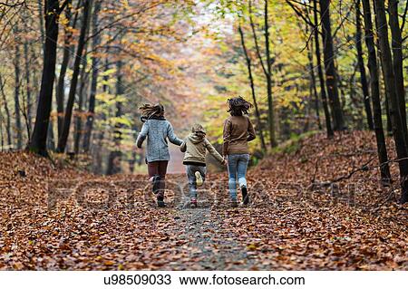 Stock Image - Girls running in autumn forest. Fotosearch