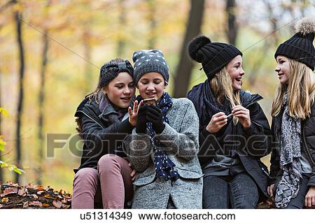 Girls using smartphone and chatting in autumn forest View Large Photo Image Stock Photo - Girls using smartphone and chatting in autumn forest. Fotosearch
