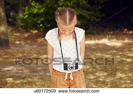 Girls with film camera hands behind back looking down View Large Photo Image Stock Photo - Girls with film camera hands behind back looking down. Fotosearch