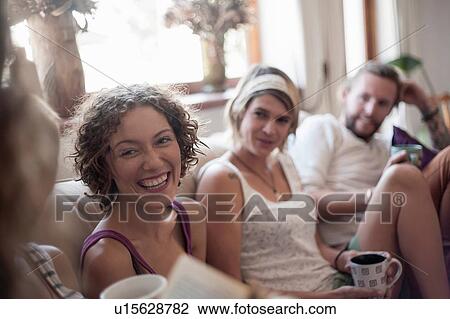 Stock Image - Group of friends, sitting on sofa, drinking tea. Fotosearch