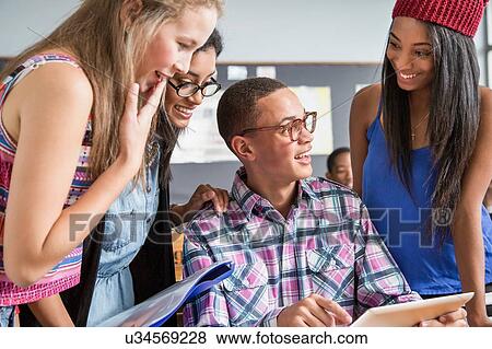 Stock Photo - Group of students in classroom, looking at digital tablet. Fotosearch