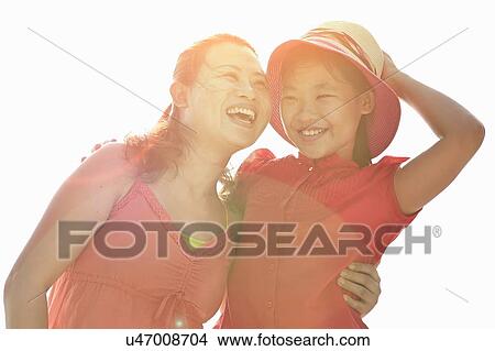 Happy mid adult woman with arm around daughter in sunlight View Large Photo Image Picture - Happy mid adult woman with arm around daughter in sunlight. Fotosearch