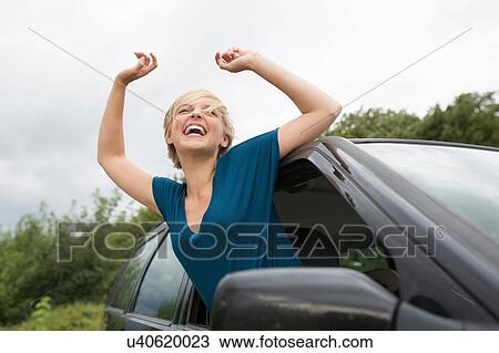Happy young woman leaning out of open car window View Large Photo Image Stock Image - Happy young woman leaning out of open car window. Fotosearch