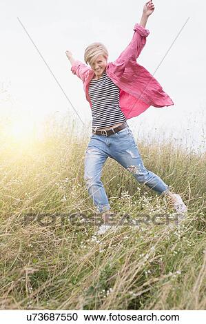 Happy young woman running in long grass View Large Photo Image Stock Image - Happy young woman running in long grass. Fotosearch