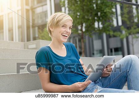 Happy young woman using digital tablet on city stairway View Large Photo Image Stock Photo - Happy young woman using digital tablet on city stairway. Fotosearch