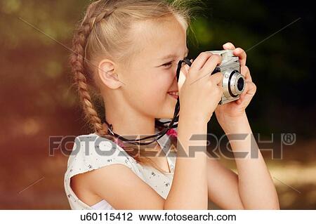 Stock Image - Head and shoulder side view of girl using film camera. Fotosearch
