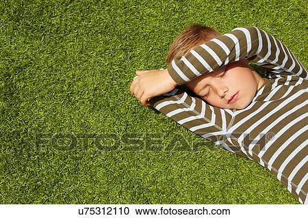 High angle view of boy lying on grass shielding face eyes closed View Large Photo Image Stock Image - High angle view of boy lying on grass shielding face eyes closed. Fotosearch