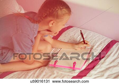 High angle view of girl kneeling on bed writing in notebook View Large Photo Image Stock Image - High angle view of girl kneeling on bed writing in notebook. Fotosearch