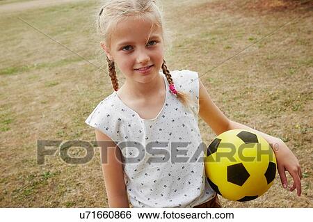 High angle view of girl with pigtails holding soccer ball looking at camera smiling View Large Photo Image Stock Photograph - High angle view of girl with pigtails holding soccer ball looking at camera smiling. Fotosearch