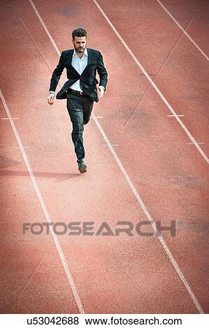 Stock Photo - High angle view of mid adult man running on racetrack. Fotosearch