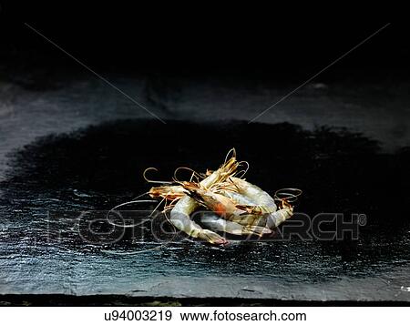 Stock Photo - High angle view of pile of raw Madagascan prawns on wet slate. Fotosearch