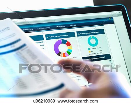 Investor checking performance of financial portfolio online whilst reviewing investment statement View Large Photo Image Stock Photo - Investor checking performance of financial portfolio online whilst reviewing investment statement. Fotosearch