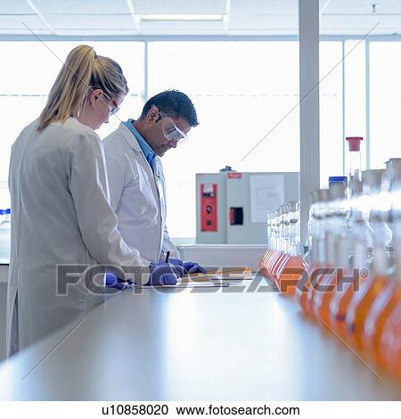 Stock Image - Laboratory chemists inspecting food colouring in laboratory. Fotosearch