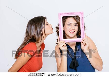 Lesbian couple fooling around with pink picture frame smiling, puckering lips View Large Photo Image Stock Image - Lesbian couple fooling around with pink picture frame smiling, puckering lips. Fotosearch