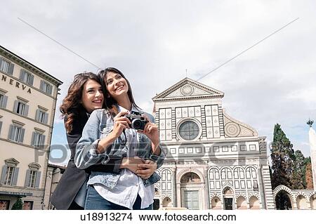 Lesbian couple holding digital camera hugging in front of church, Piazza Santa Maria, Novella Florence, Tuscany, Italy View Large Photo Image Picture - Lesbian couple holding digital camera hugging in front of church, Piazza Santa Maria, Novella Florence, Tuscany, Italy. Fotosearch