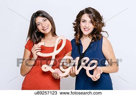 Lesbian couple holding the word love, looking at camera smiling View Large Photo Image Stock Image - Lesbian couple holding the word love, looking at camera smiling. Fotosearch