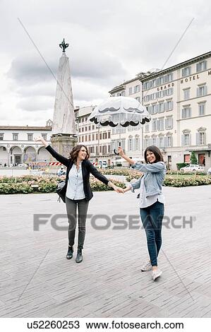 Lesbian couple holding umbrella fooling around holding hands smiling, Piazza Santa Maria Novella, Florence, Tuscany, Italy View Large Photo Image Stock Image - Lesbian couple holding umbrella fooling around holding hands smiling, Piazza Santa Maria Novella, Florence, Tuscany, Italy. Fotosearch