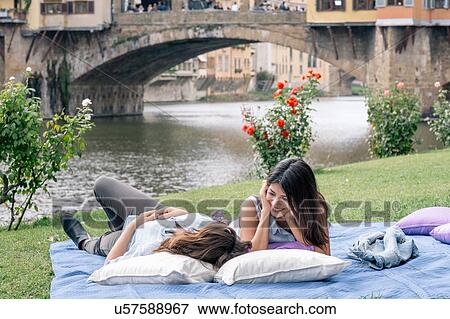 Stock Photo - Lesbian couple lying on blanket in front of Ponte Vecchio over river Arno, Florence, Tuscany, Italy. Fotosearch