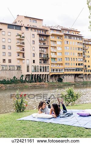 Lesbian couple lying on front on blanket next to Arno river, Florence, Tuscany, Italy View Large Photo Image Stock Image - Lesbian couple lying on front on blanket next to Arno river, Florence, Tuscany, Italy. Fotosearch