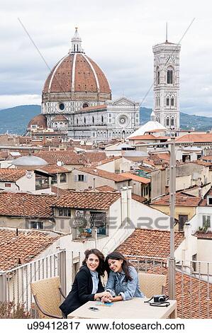 Stock Photo - Lesbian couple sitting at table on roof terrace in front of Giotto's Campanile and Florence Cathedral, Tuscany, Italy. Fotosearch