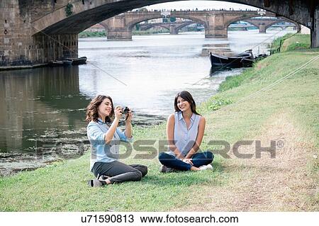 Lesbian couple sitting on arno river bank in front of Ponte Vecchio holding digital camera smiling, Florence, Tuscany, Italy View Large Photo Image Stock Image - Lesbian couple sitting on arno river bank in front of Ponte Vecchio holding digital camera smiling, Florence, Tuscany, Italy. Fotosearch
