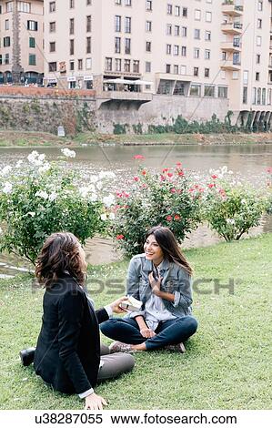 Lesbian couple sitting on grass next to Arno river giving, receiving gift, Florence, Tuscany, Italy View Large Photo Image Stock Photography - Lesbian couple sitting on grass next to Arno river giving, receiving gift, Florence, Tuscany, Italy. Fotosearch
