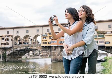 Lesbian couple standing hugging in front of Ponte Vecchio and river Arno using digital camera to take photograph, Florence, Tuscany, Italy View Large Photo Image Stock Image - Lesbian couple standing hugging in front of Ponte Vecchio and river Arno using digital camera to take photograph, Florence, Tuscany, Italy. Fotosearch