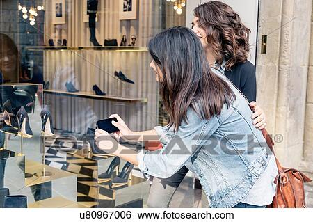 Lesbian couple using smartphone to take photograph of shoes through shoe shop window, Florence, Tuscany, Italy View Large Photo Image Stock Photograph - Lesbian couple using smartphone to take photograph of shoes through shoe shop window, Florence, Tuscany, Italy. Fotosearch