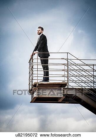 Stock Image - Low angle side view of mid adult man on stairs wearing suit looking away. Fotosearch