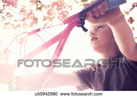 Low angle view of boy on BMX bicycle looking away View Large Photo Image Stock Image - Low angle view of boy on BMX bicycle looking away. Fotosearch
